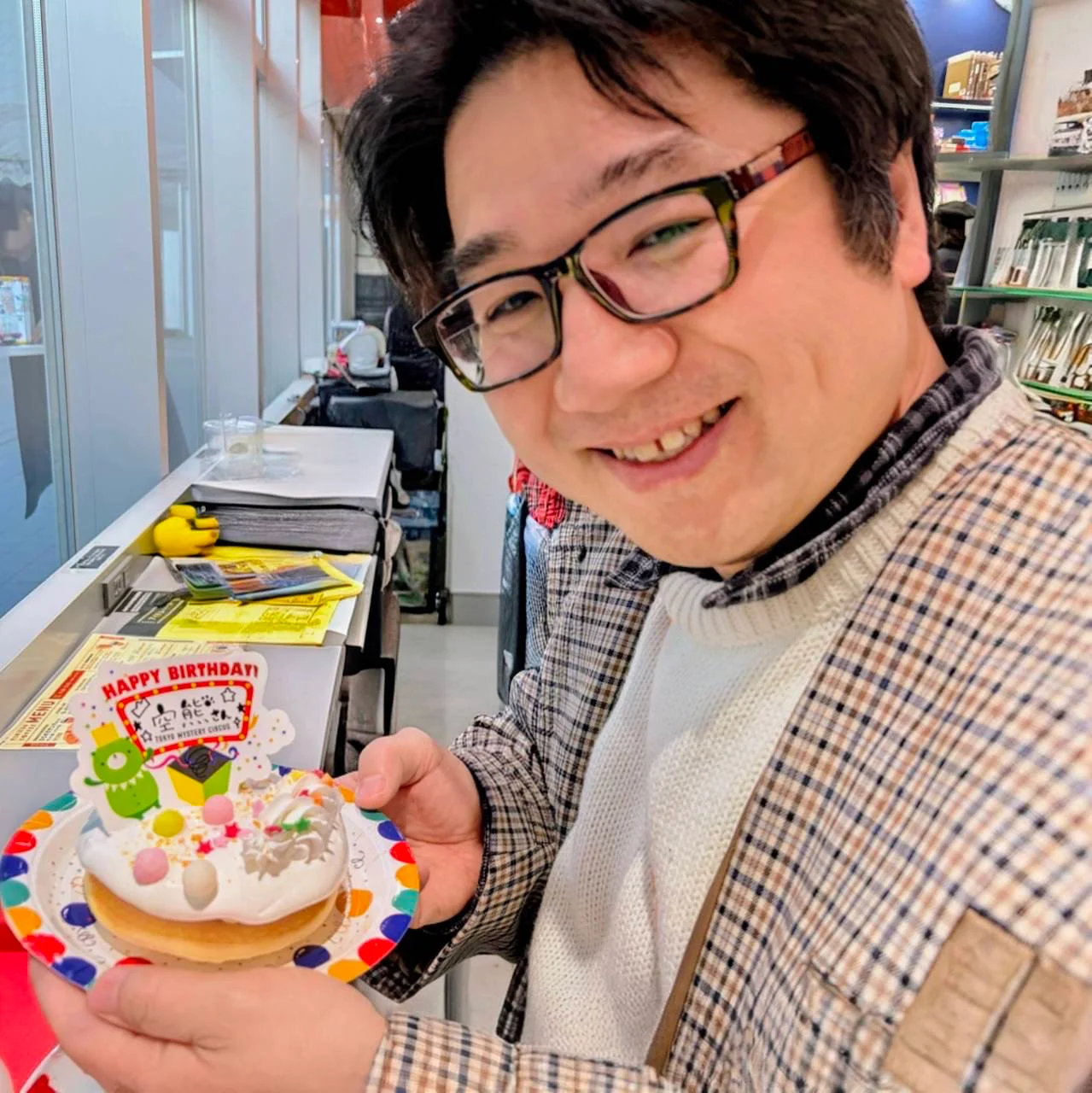 パンケーキを前に笑顔の行政書士 三田寺。誕生日の謎解きカフェにて。